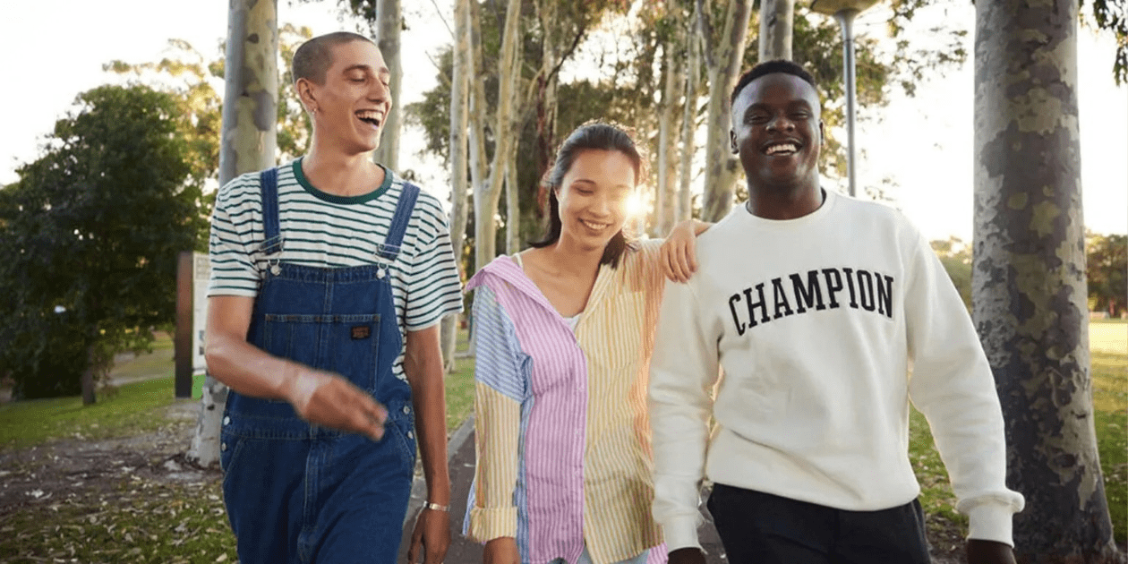Three Curtin University students walking campus and smiling.