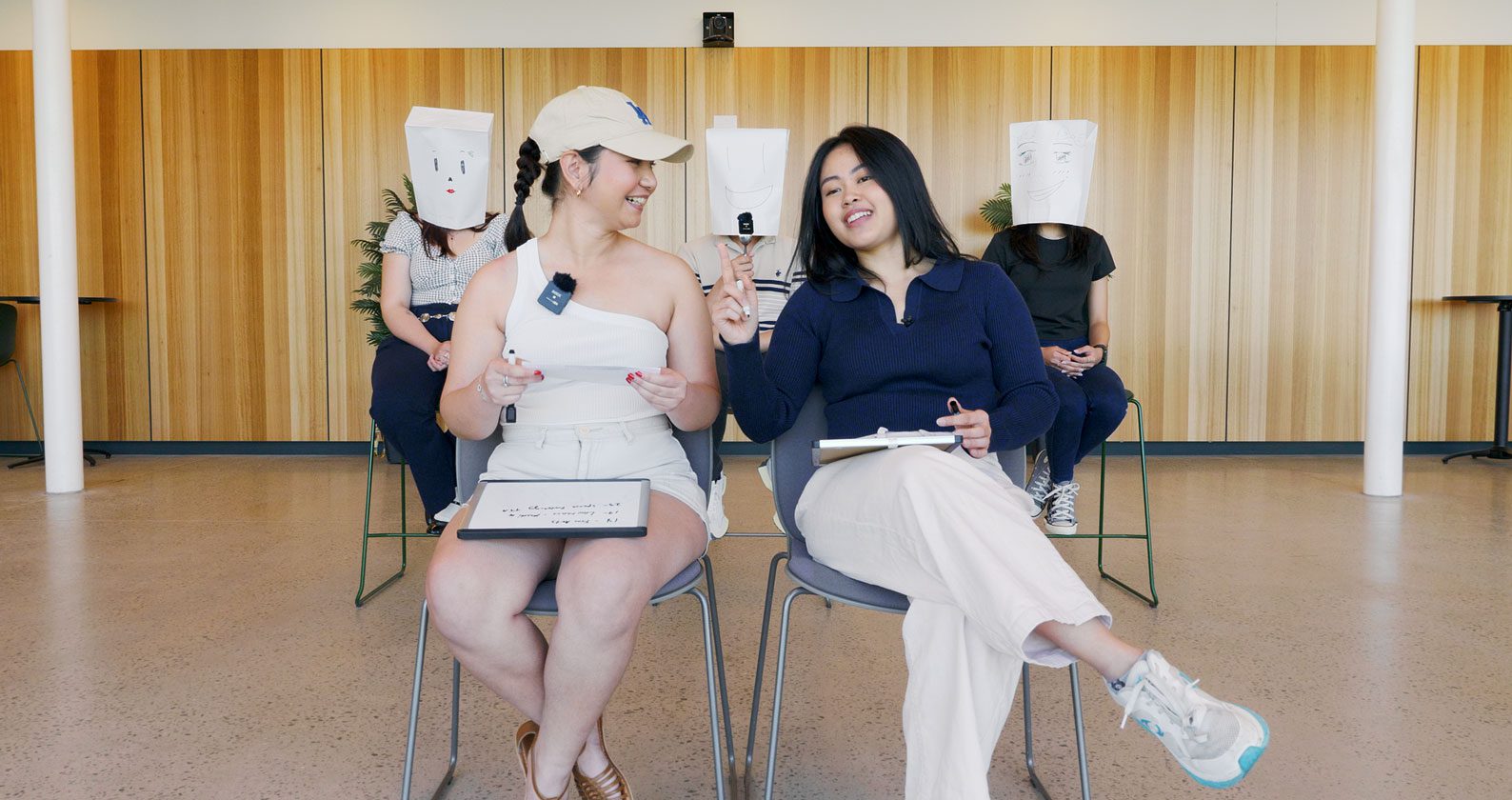 Devna and Celena sitting in front of masked students.