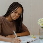 Student studing at home holding a pen and writing on paper.