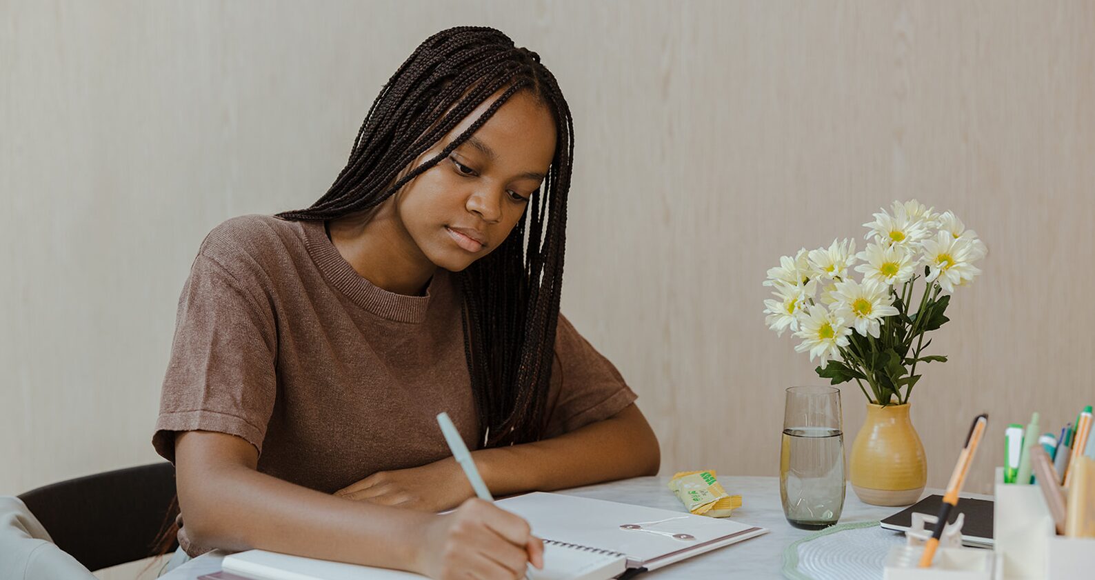 Student studing at home holding a pen and writing on paper.