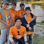 Group of five students wearing orange CV! t-shirts standing outdoors.