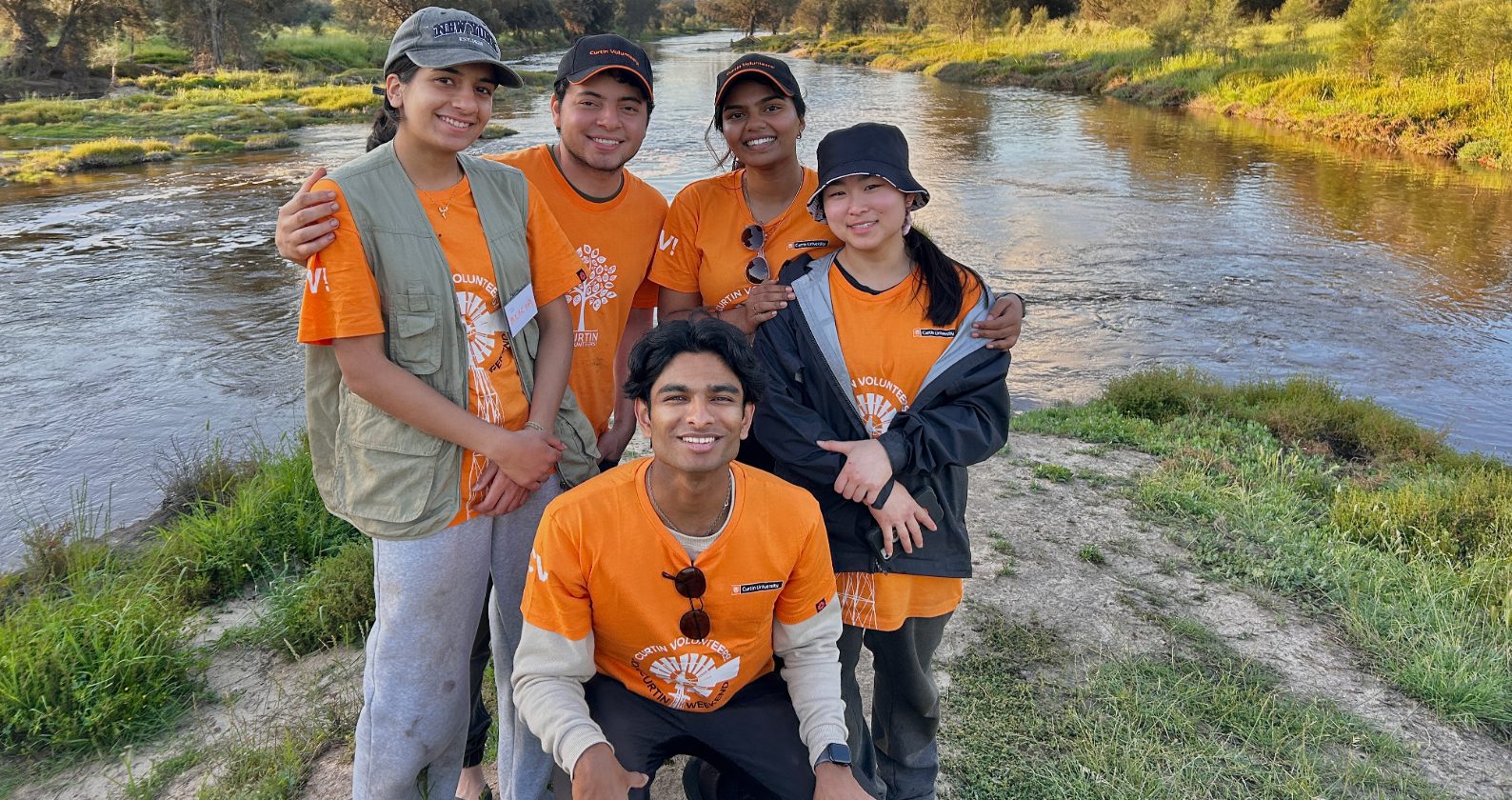 Group of five students wearing orange CV! t-shirts standing outdoors.