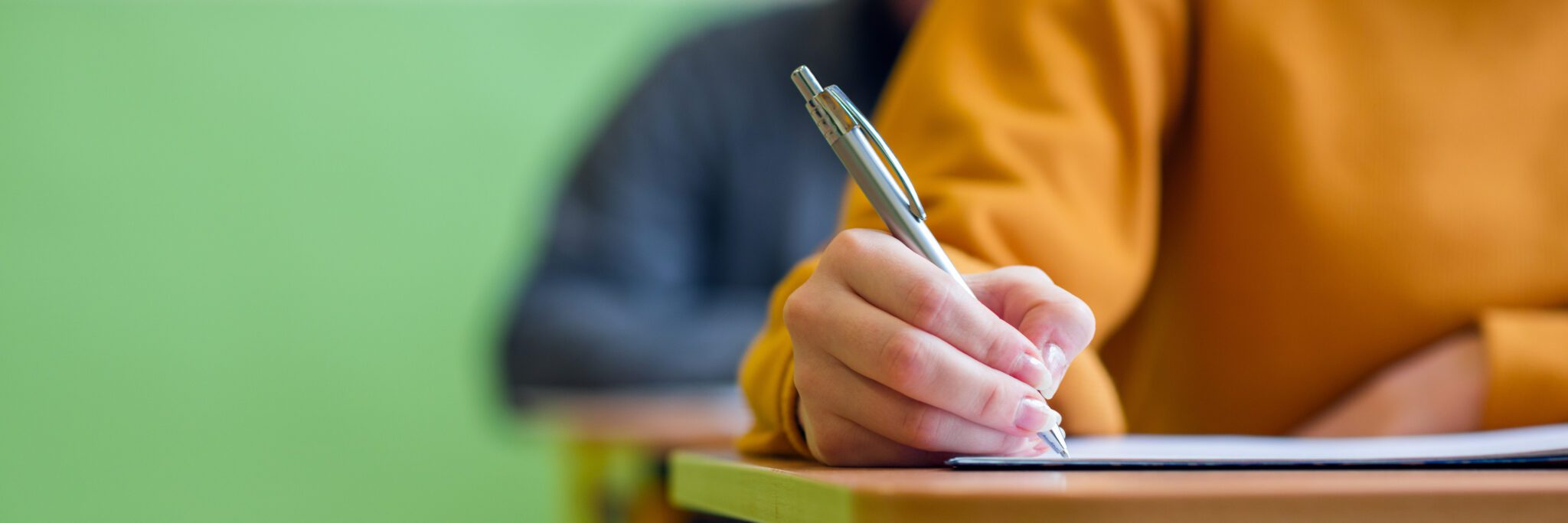 Student taking exam in classroom. Education test and literacy concept. Cropped shot, hand detail.
