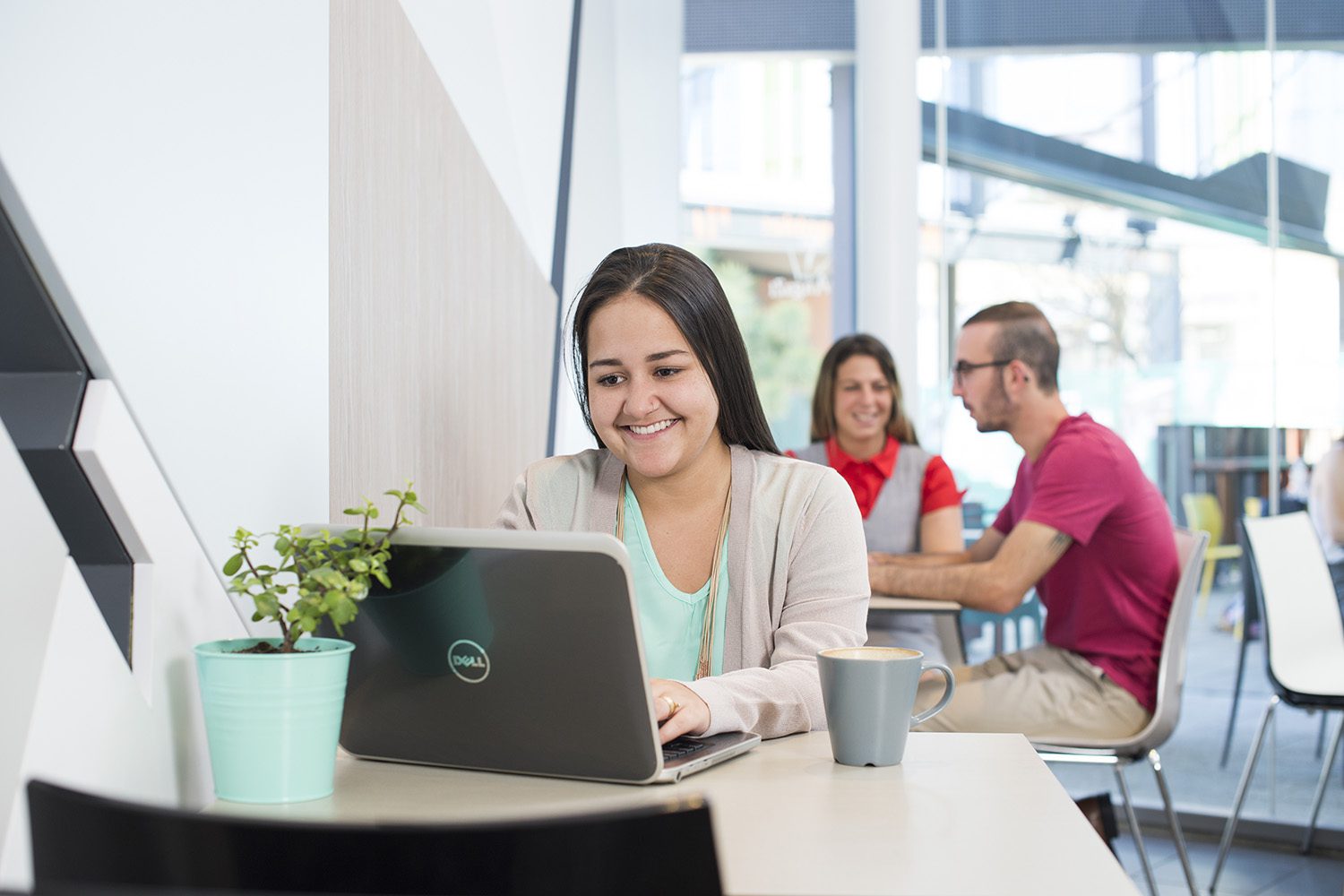Woman with a laptop open in front of her, sitting in a cafe