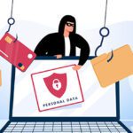 A masked person standing behind a laptop.