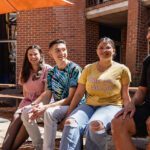 Four students sit together on a bench out the front of the Centre of Aboriginal Studies.