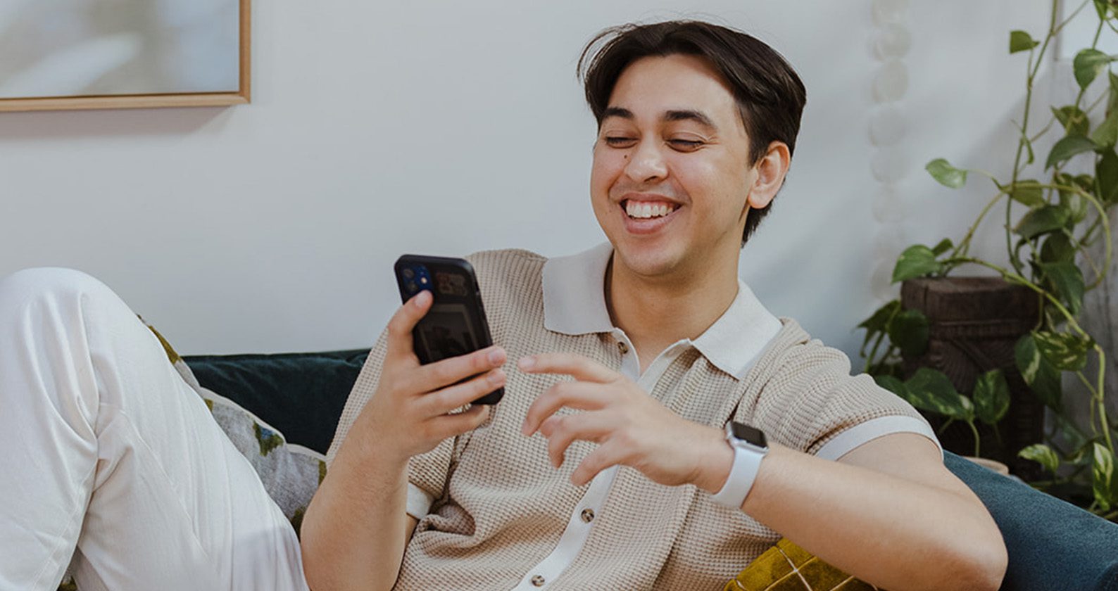 A male student smiling while looking at his phone