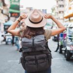 A woman wearing a backpack in front of a busy street,