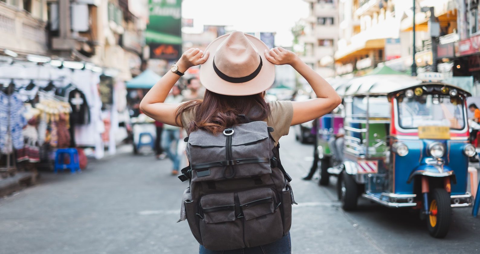 A woman wearing a backpack in front of a busy street,