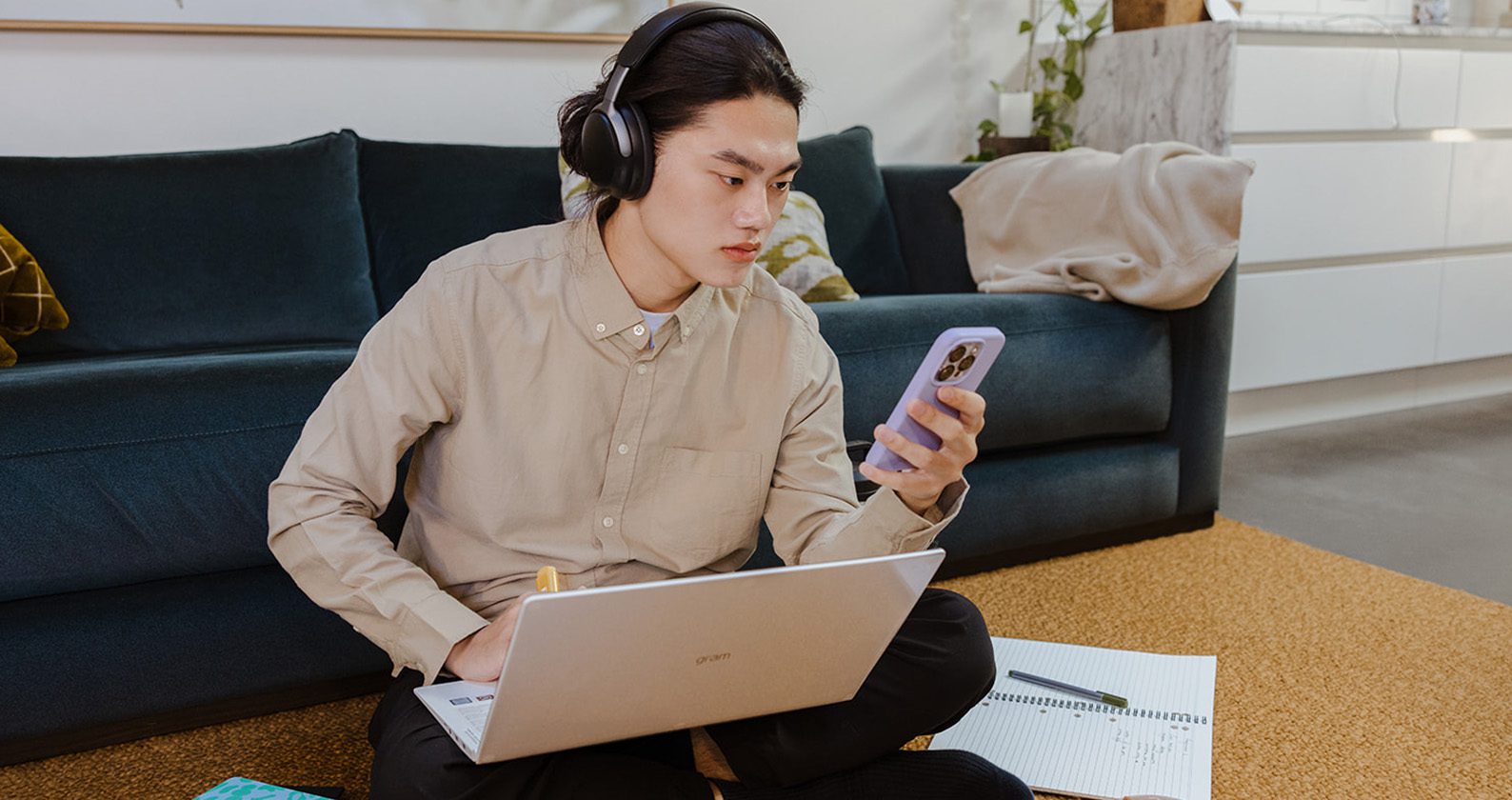 Student working on their laptop sitting on the floor at home.