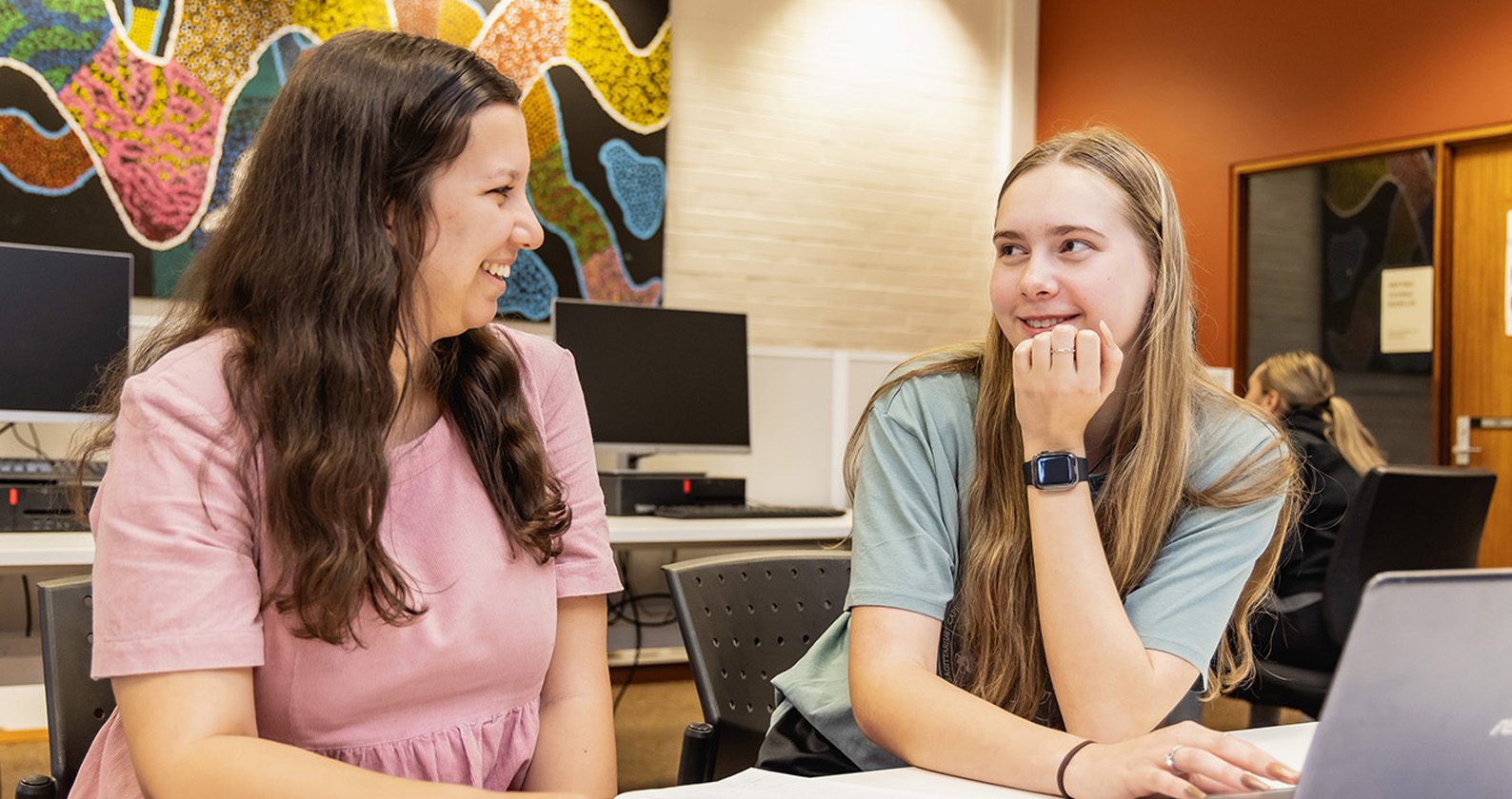 Two students looking at each other and smiling.