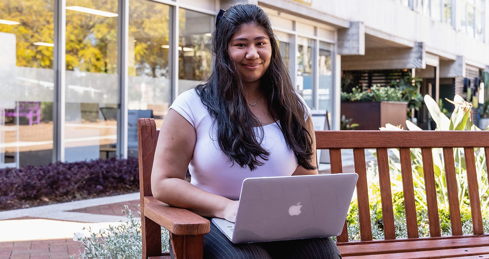 Person sitting on a bench on a laptop.