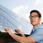 A person touching a solar panel.