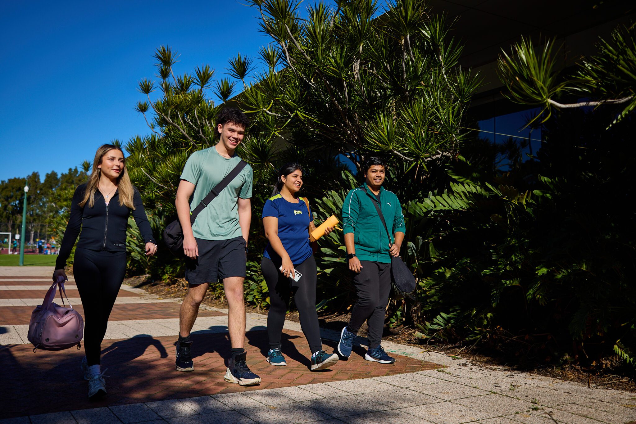 Four students walking together outdoors at Curtin Perth.