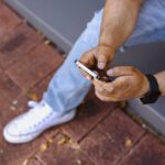 Student sitting on a step with a phone in their hands.
