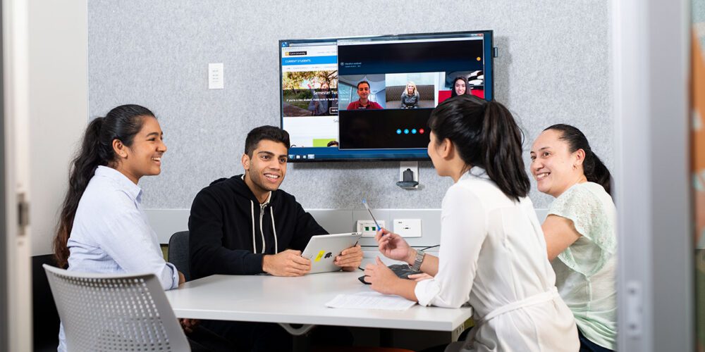 Curtin students sitting around a table and smiling.