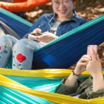 Two students sitting on hammocks.