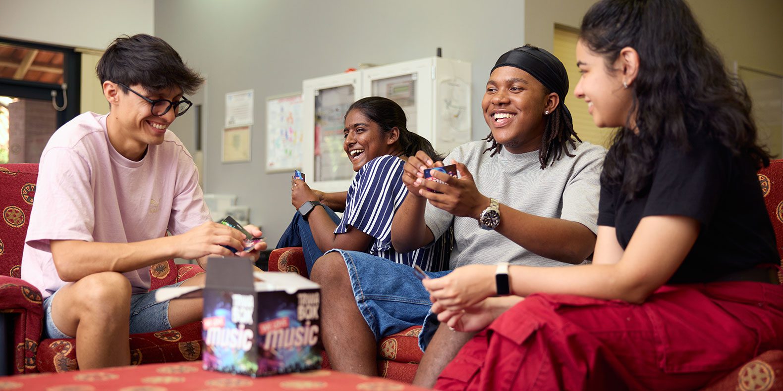 Four students sitting and laughing in Curtin accommodation