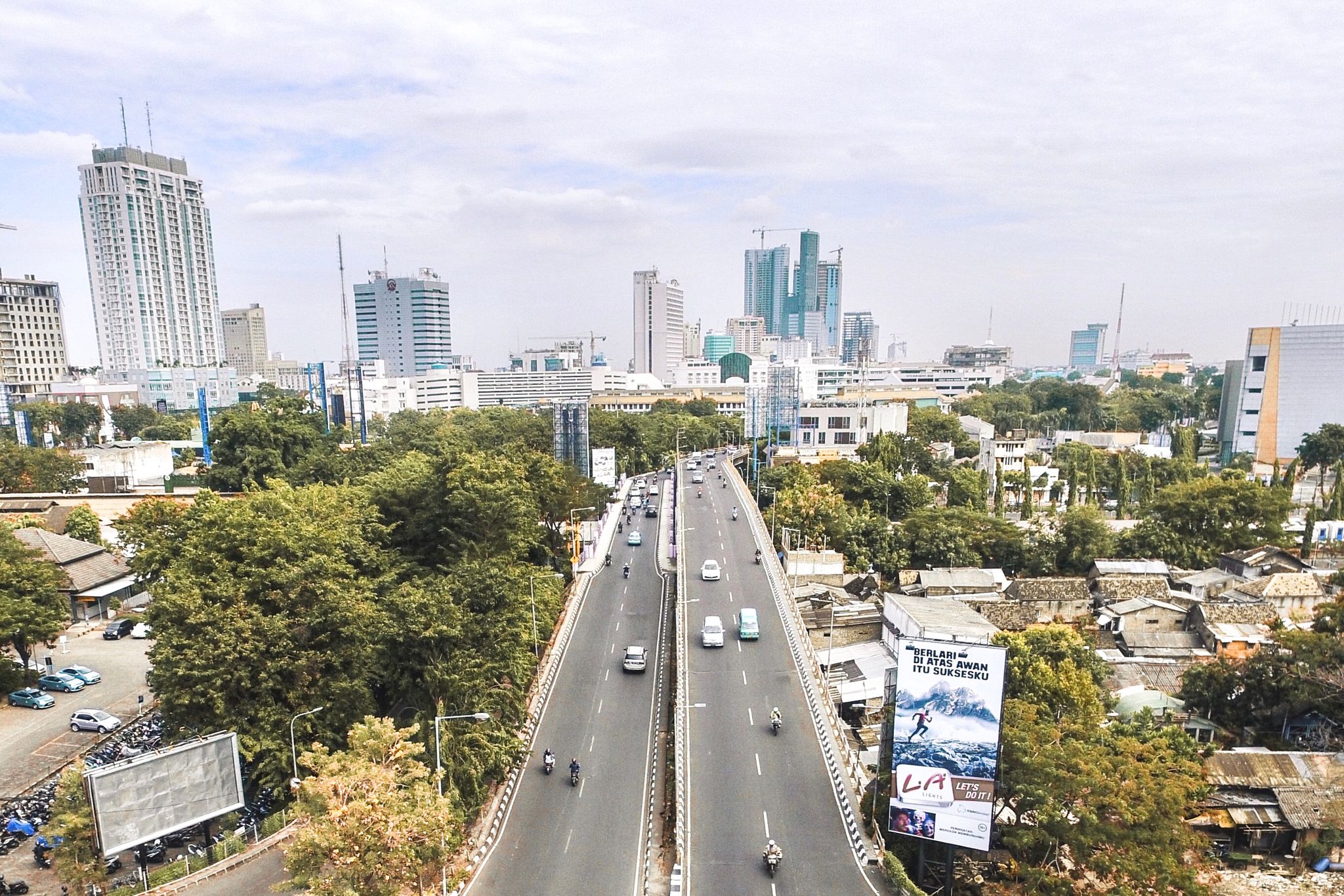 Aerial shot of Surabaya cityscape showcasing roads, buildings, and greenery.