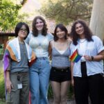 Four students standing together holding pride flags