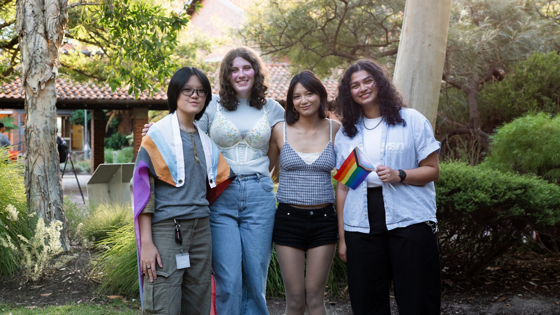Four students standing together holding pride flags