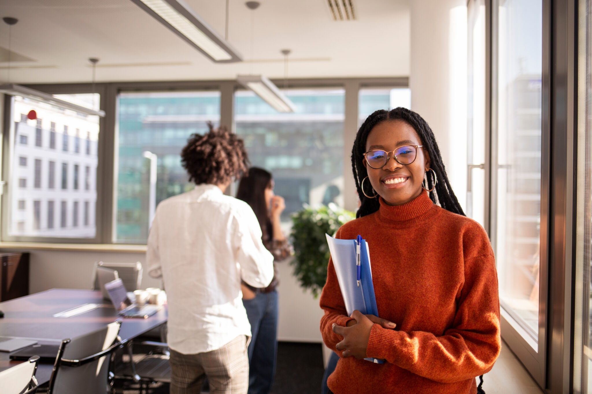 A female student carrying her books and smiling at the camera