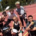 A diverse group of students playing pickleball