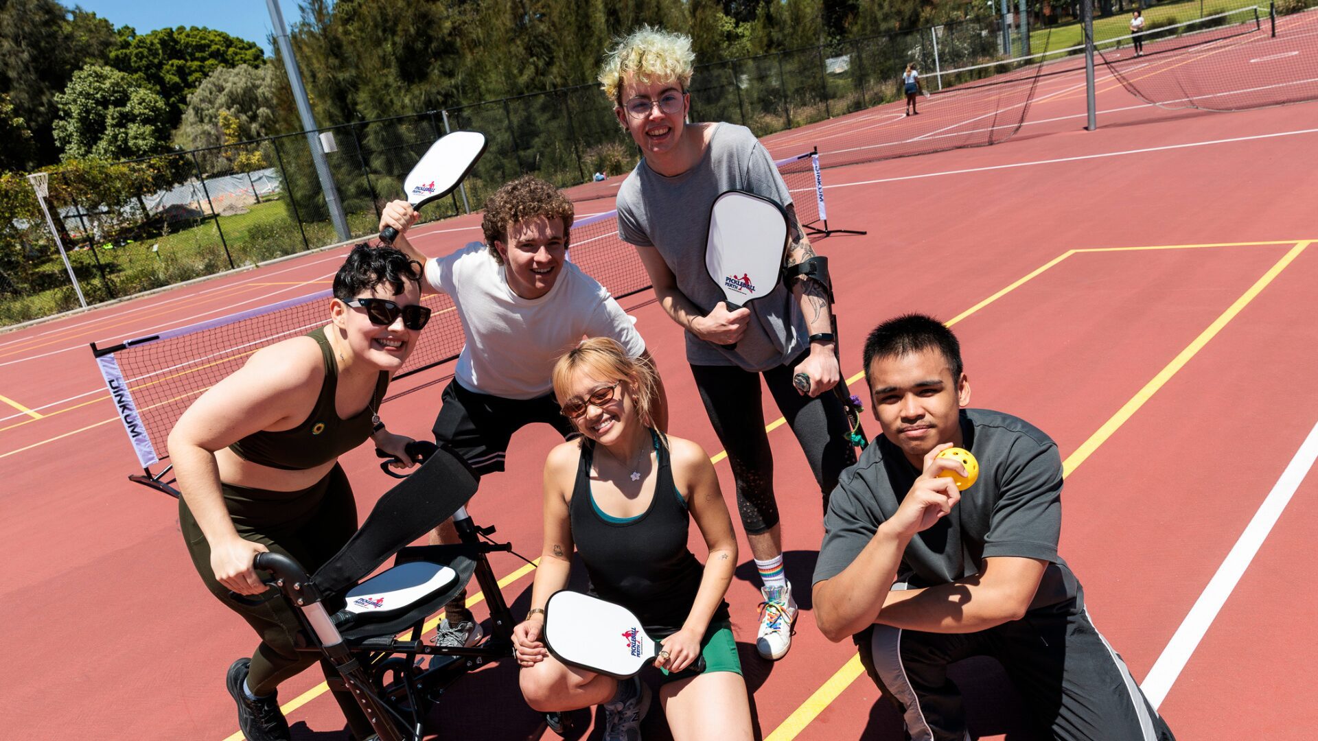 A diverse group of students playing pickleball