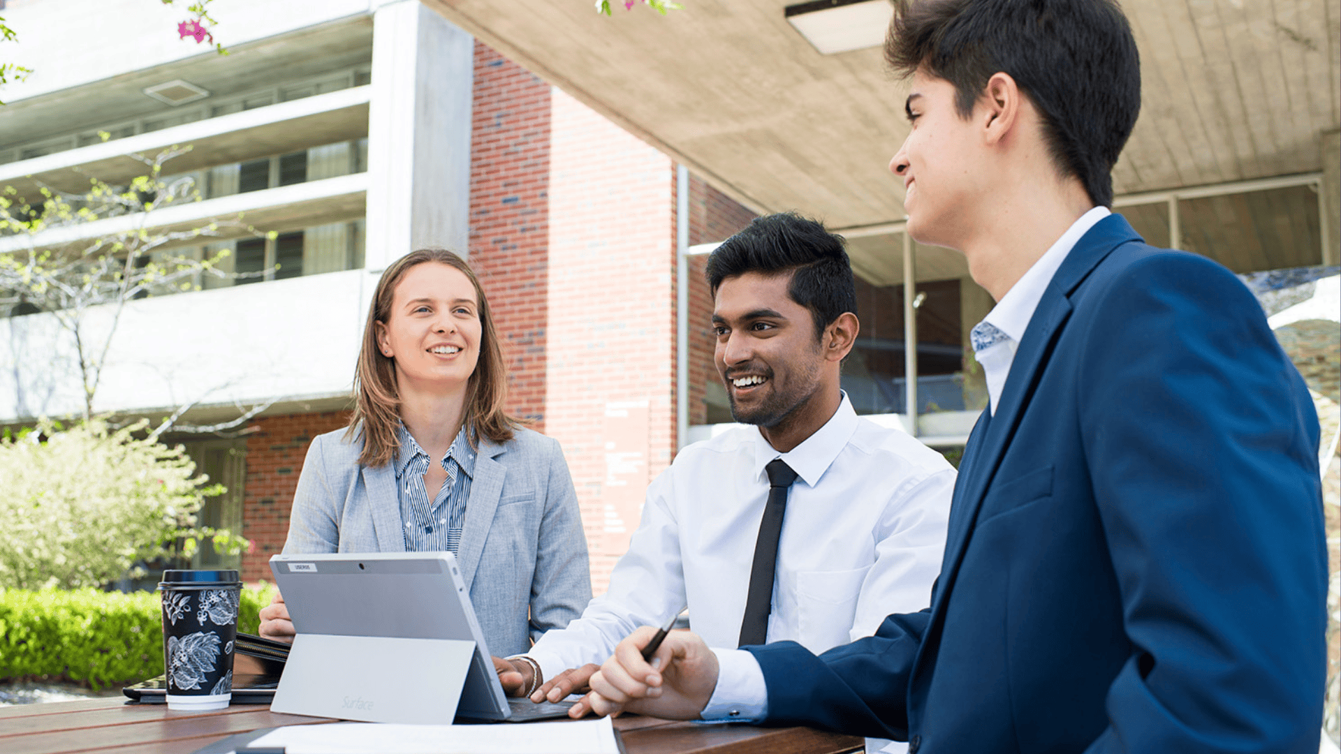 Three students in business attire chatting