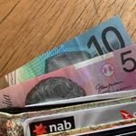 Close-up of Australian dollar bills and credit cards in a wallet on a wooden surface.