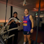 Two people holding exercise testing equipment beside a treadmill in a sports science lab.