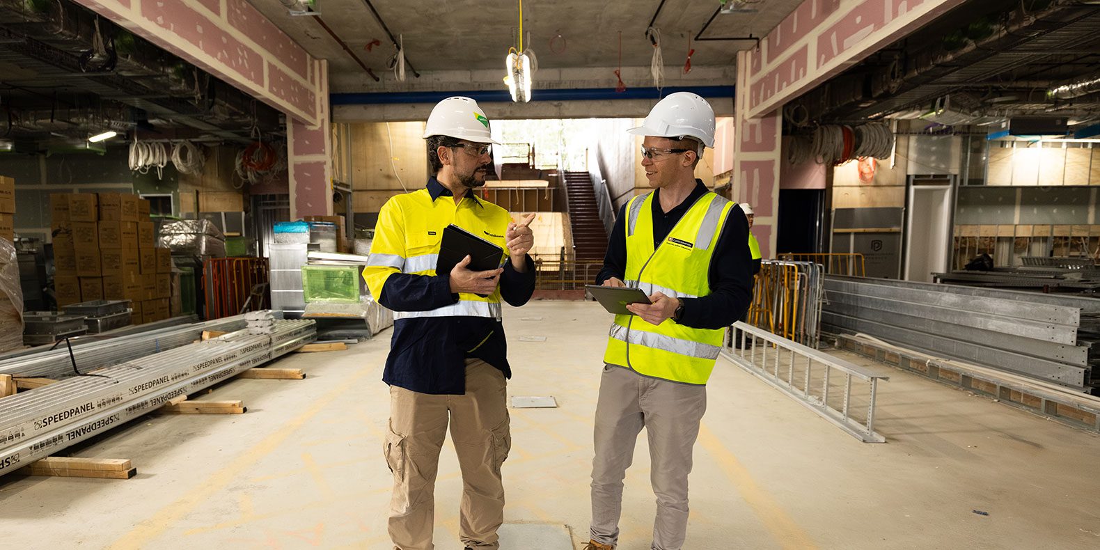 Student Nathan Moore on the right on a construction site speaking with a supervisor on the left.