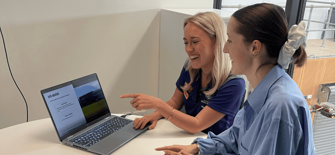 Two people looking at a laptop together at a table.