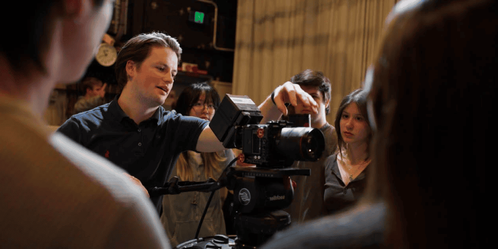 Students watch an instructore operate a camera in a virtual production workshop.