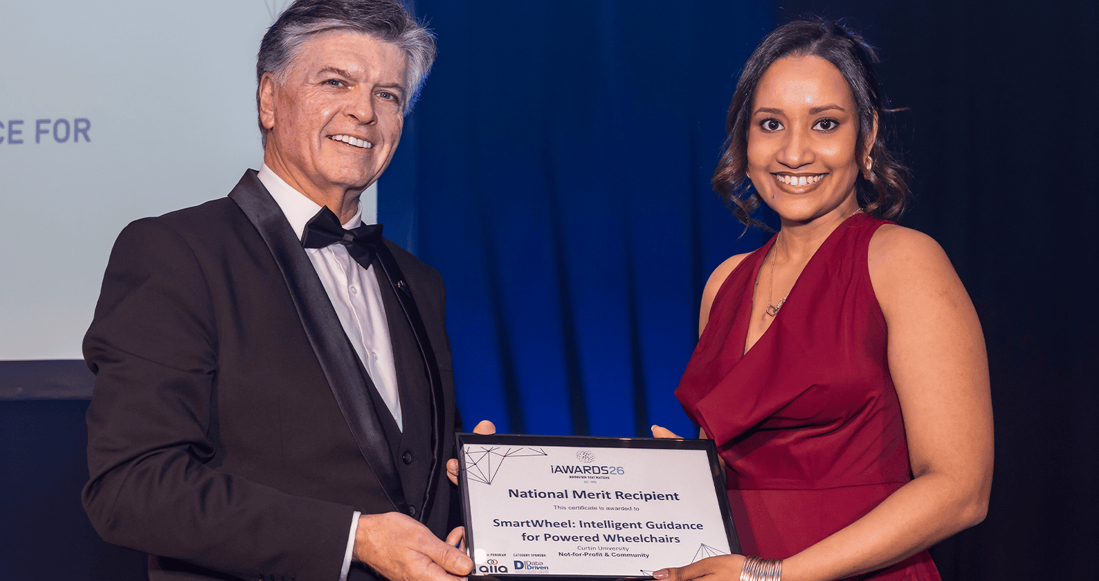 Award recipient holding a technology innovation certificate at an awards ceremony.