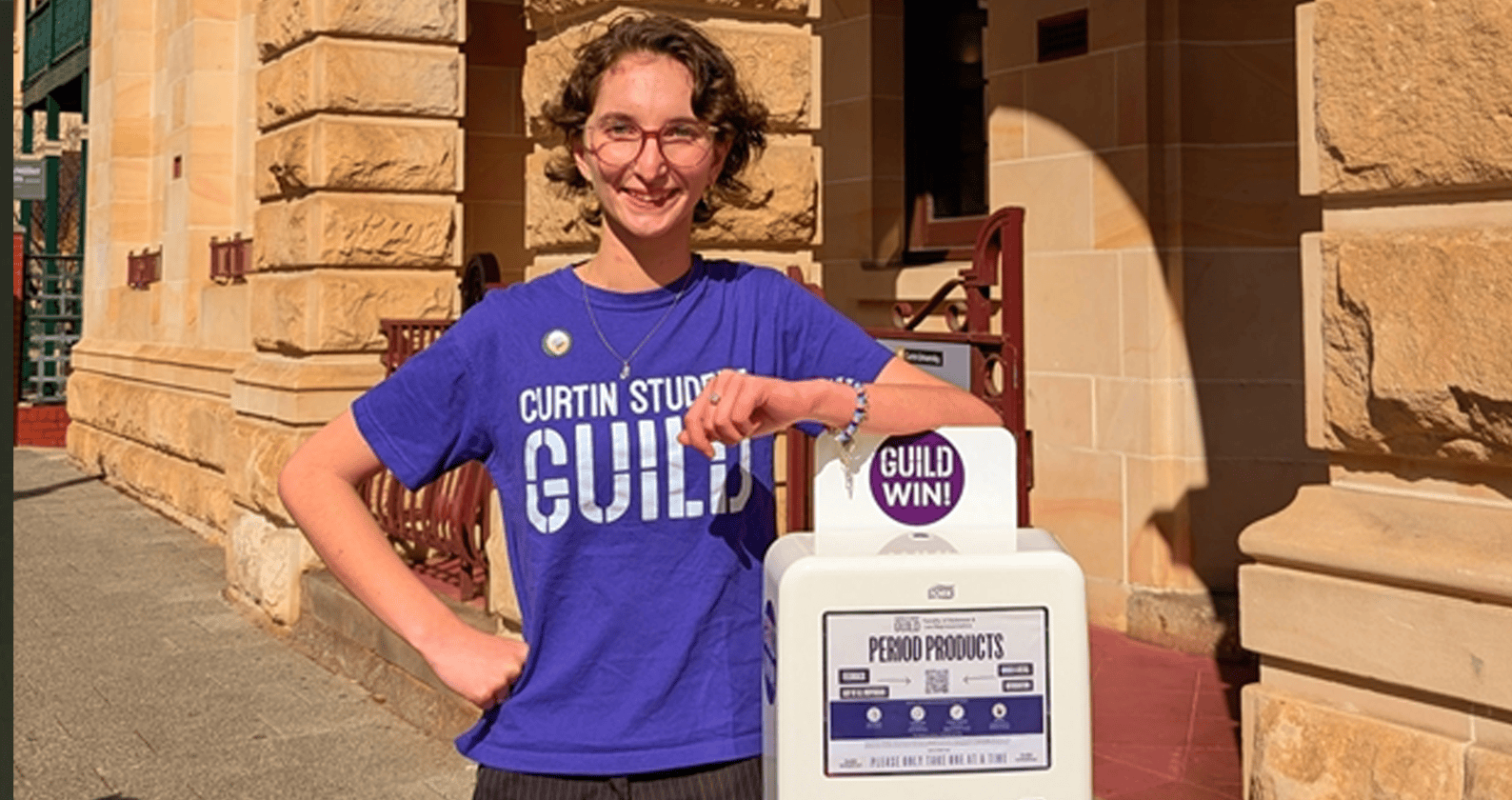 Student standing beside a campus period product dispenser.