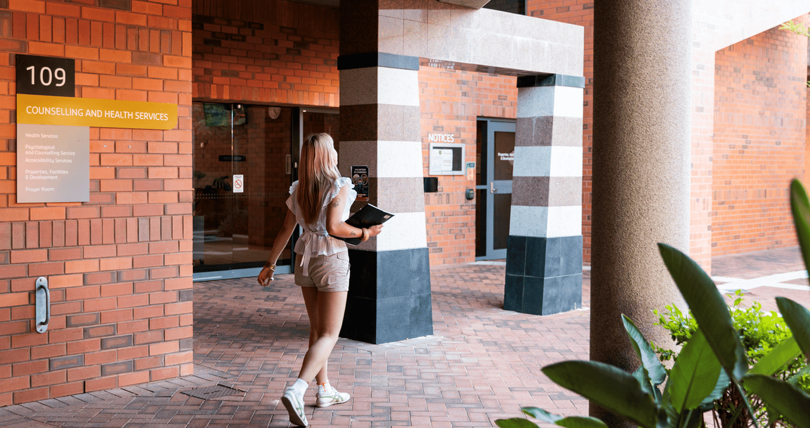Person walking towards the Building 109 Counselling and Health Services entrance.