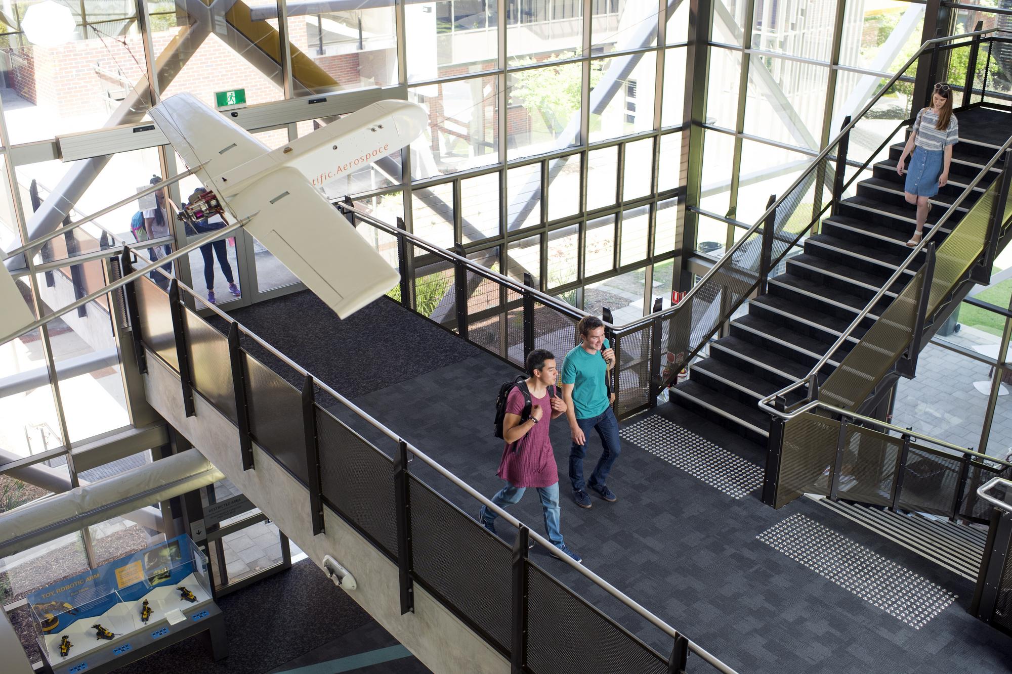 Top-down shot of students walking through mezzanine of building on campus