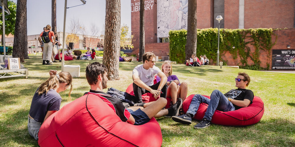 Five people sitting on bean bags talking outdoors