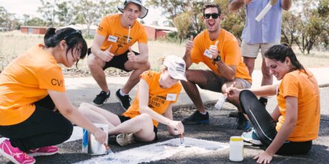 Curtin Volunteer! students painting on the road and smiling