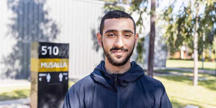 A Muslim male student smiling in front of the Musalla