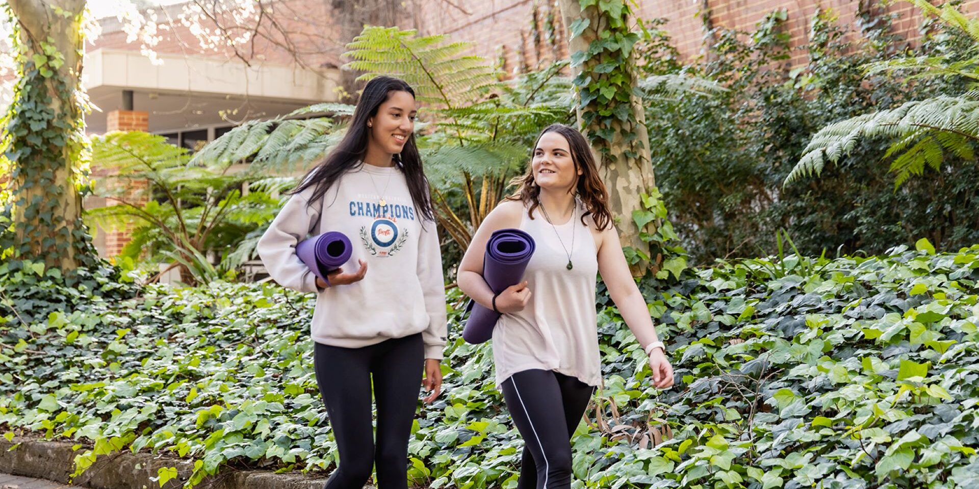 2 students walking with yoga mats