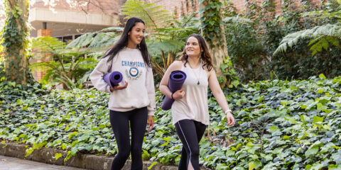 2 students walking and carrying yoga mats