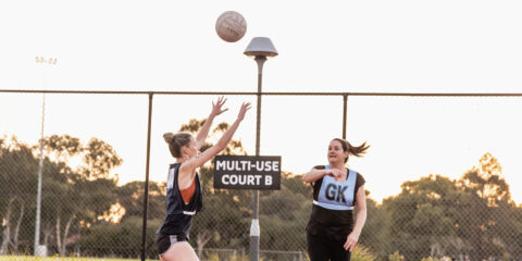 Two woman playing netball at netball courts