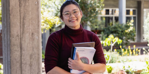 a female student smiling and holding text books