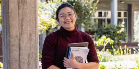 female student holding textbooks and smiling