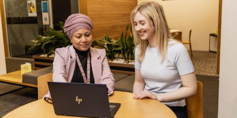 Two people looking at a laptop. The person on the left is giving advice.