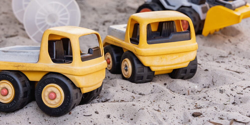 Close up of toy, yellow, trucks in the sand pit.
