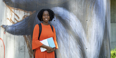 a female student smiling next to a wall