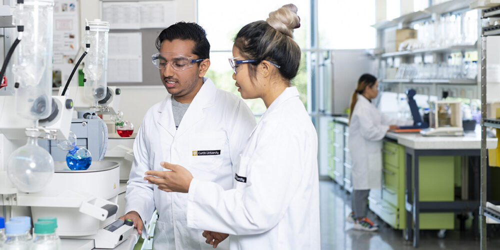 Two people in lab coats analysing chemical samples